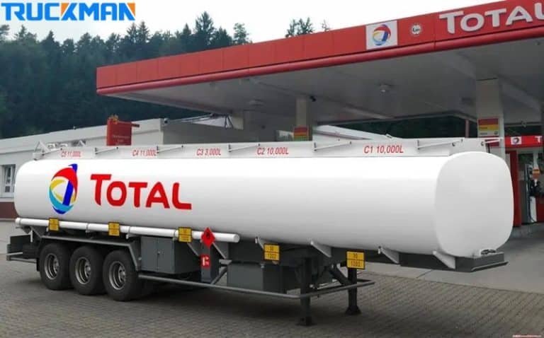 Um camião-cisterna branco com a marca TOTAL numa estação de serviço, destacando a sua grande capacidade de volume para o transporte de produtos petrolíferos