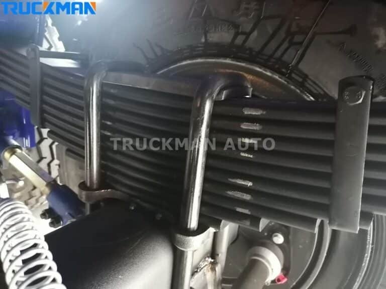 Grande plano da suspensão de molas de lâmina num semirreboque de caixa aberta da TRUCKMAN AUTO.