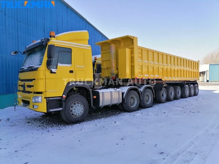 Semirreboque amarelo de vários eixos com descarga traseira concebido para o transporte de materiais pesados a granel em condições de neve